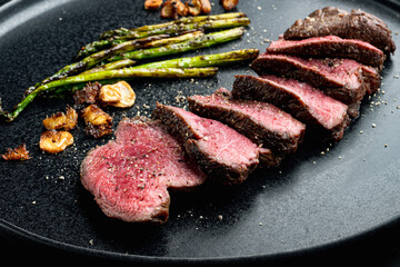 Grilled fillet beef steaks, with onion and asparagus, on plate - obrazy, fototapety, plakaty