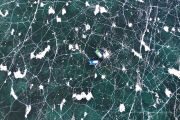 Aerial view on the ice pattern of Lake Baikal with cracks. A hovercraft transports tourists across the ice. Winter travel. Aerial view.