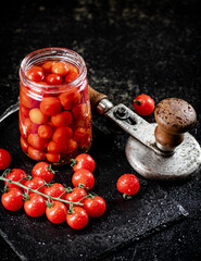 Pickled tomatoes in a jar on a stone board. 