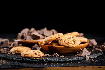 Cookies with pieces of milk chocolate on a stone board. 