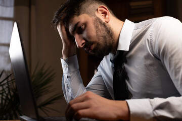 jeune employé de bureau concentré qui travaille tard, assis devant son ordinateur portable
