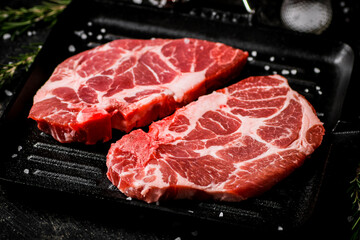 Raw pork steak in a frying pan. 
