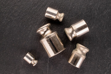 Several metal weights for old jewelry scales on slate stone, macro, top view.