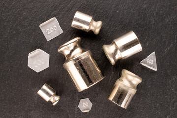 Several metal weights for old jewelry scales on slate stone, macro, top view.