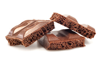 Pieces of broken aerated chocolate on a white background close-up. Chocolate