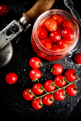 Pickled tomatoes in a jar on a stone board. 