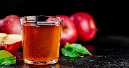 A full glass of apple juice with leaves.