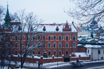 Obraz premium Krakow, Poland - December 20, 2022. Cityscape. Traditional European Old Town Street with Red Building (The Straszewski Palace) and a carriage with horses. European City Architecture.
