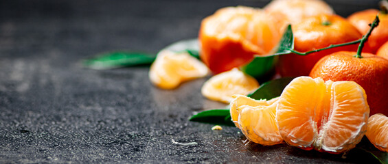 Ripe tangerines with foliage. On a black background.