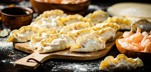 Raw dumplings gyoza with shrimp on a cutting board. 