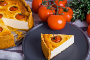 Pie with cream cheese decorated with tomatoes.  Piece of tart with vegetables on a black plate, top view. Homemade pastry.