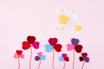 Multicolored crocheted hearts are laid out in the shape of a flower clover on a lilac background. Happy Valentine's Day, Mother's Day and birthday greeting card.