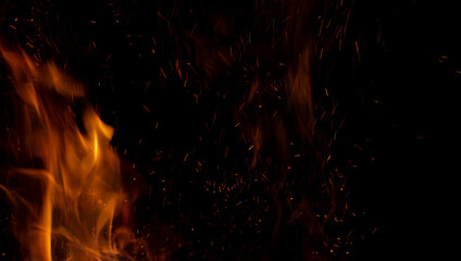 Fototapeta na wymiar Sparks and fire on a black background. Abstract blurred bonfire with sparks and flames.