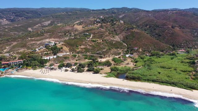 Aerial drone video of famous bay and organised sandy beach of Livadi Armenistis, popular for surfing sports, Ikaria island, Northeast Aegean, Greece