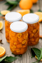 Homemade candied peels orange syrup in glass jar , on the background of sliced oranges