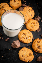 Homemade cookies with pieces of milk chocolate and a glass of milk. 