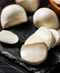 Pieces of mozzarella cheese on a stone board. 