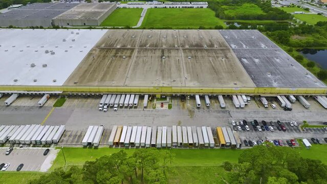 Aerial View Of Large Commercial Loading Bay With Many Delivery Trucks Unloading And Uploading Retail Goods For Nationwide Distribution. Global Economy Concept.