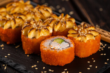 California sushi roll with crab, avocado and tobiko caviar served on black board close-up - Japanese food