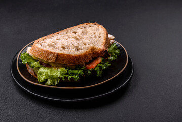 Fresh tasty sandwich with chicken, tomatoes and lettuce on a black plate