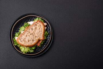 Fresh tasty sandwich with chicken, tomatoes and lettuce on a black plate