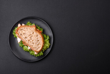 Fresh tasty sandwich with chicken, tomatoes and lettuce on a black plate