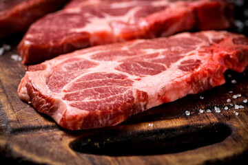 Raw pork steak on a wooden cutting board. 