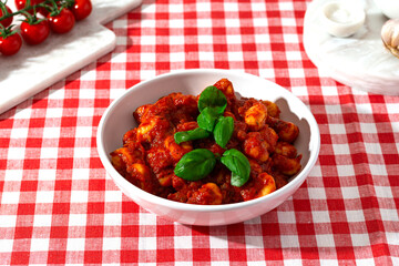 gnocchi with tomato sauce and basil on a red checkered tablecloth