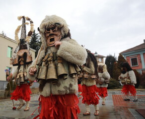 Fototapeta premium Breznik, Bulgaria - January 21, 2023: Unidentified people with traditional Kukeri costume are seen at the Festival of the Masquerade Games Surova in Breznik, Bulgaria