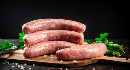 Raw sausages on a cutting board with parsley. 