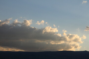 Fototapeta premium Dramatic golden sky sunset clouds over the grass fields. Sunset over the mountains