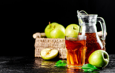 Apple juice in a jug and a glass on the table. 