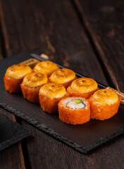 Sushi roll with crab, avocado and tobiko caviar served on black board close-up - Japanese asian food