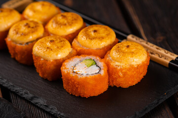 Sushi roll with crab, avocado and tobiko caviar served on black board close-up - Japanese asian food