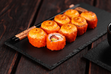 Sushi roll with salmon, avocado and tobiko caviar served on black board close-up - Japanese asian food