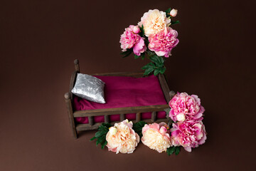 the wooden bed is decorated with pink peonies. props for a photo shoot of newborns. furniture for dolls