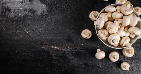 Fresh mushrooms champignons in a bowl on the table. 