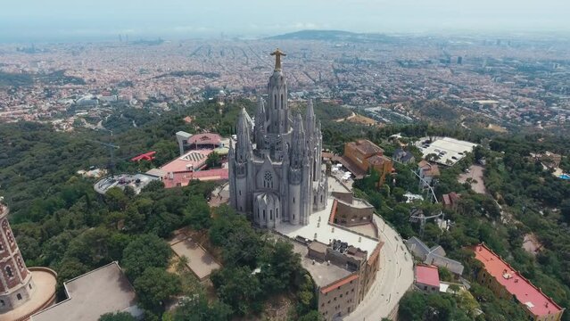 Fantastic overview aerial footage around the Expiatory Church of the Sacred Heart of Jesus (Temple Expiatori del Sagrat Cor) at the dawn in Tibidabo mountain in Barcelona.