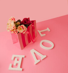 .A bag with a flower and the white letters LOVE on a pink pastel background