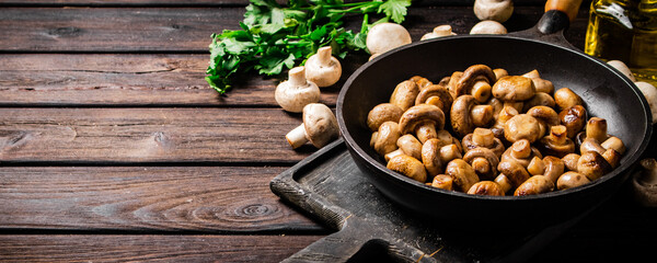 Fragrant homemade fried mushrooms in a frying pan on a cutting board. 