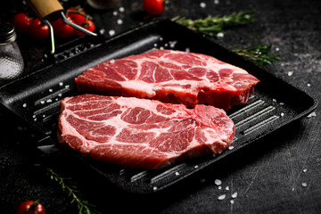 Raw pork steak in a frying pan. 