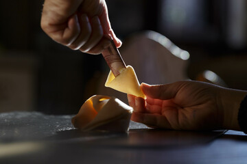A hand pulling a bill out of a fortune cookie, the hand is seen gripping the edge of the bill and pulling it out of the open fortune cookie.