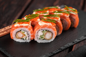 Sushi roll philadelphia with crab and cucumber and cream cheese, caviar on black background close-up. Sushi menu. Japanese food concept