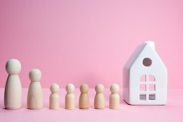 Wooden figures big family infront white house.Big family is standing near the house. Wooden figures of persons stand near a house. Housing problem for a family. Expensive houses, real estate crisis