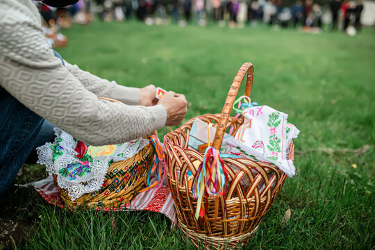 A man lights a candle on an Easter candle during an Easter Orthodox service outside. Easter basket with food for consecration with holy water.