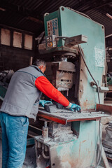 A worker in heavy industry breaks stone blocks using large machines. Granite and stone processing industry.