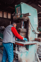 A worker in heavy industry breaks stone blocks using large machines. Granite and stone processing industry.