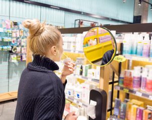 Fototapeta na wymiar Woman buying make up at cosmetics section in store. choosing cosmetics, perfumes, creams and shampoos, Using tester.