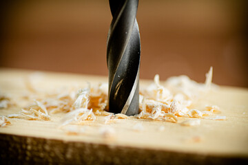 Piece of wood is drilled with shavings. 