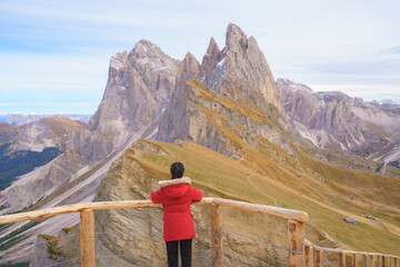 Naklejka premium Dolomite mountain landscapes, A woman looking at Seceda mountain peak in autumn in Dolomite Alps, South Tyrol, Italy